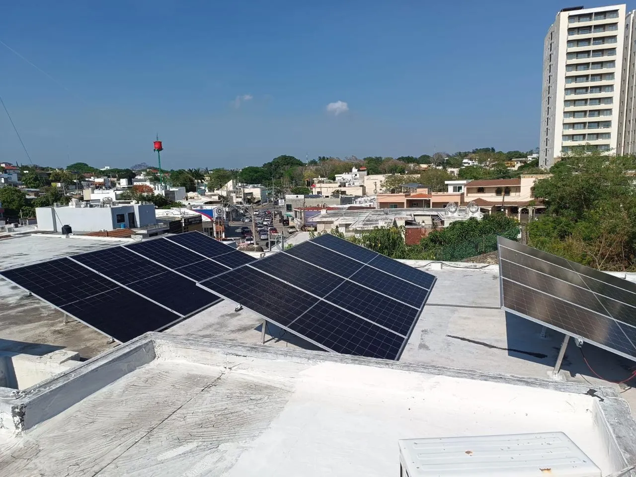 Sistema solar instalado en un techo, con el perfil de la ciudad de fondo bajo cielo despejado